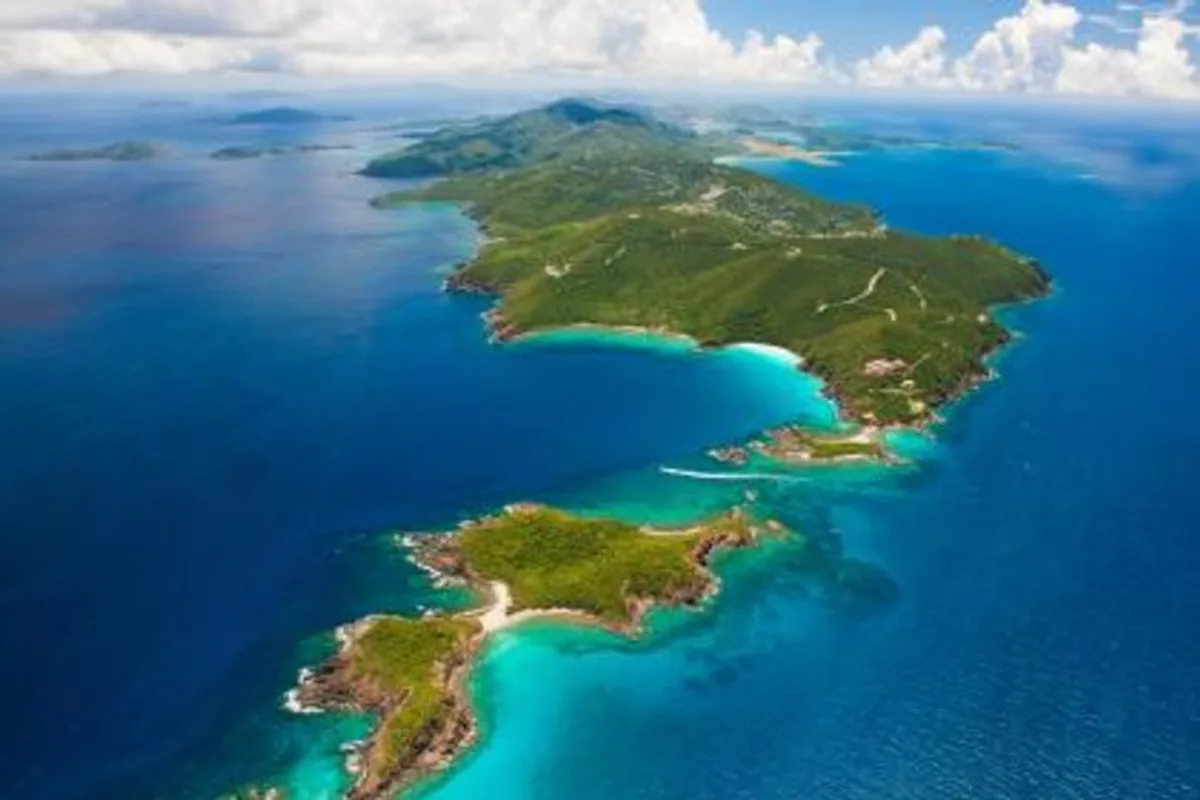 Parasailer soaring above turquoise water off Sapphire Beach during parasailing in St. Thomas USVI, St. John visible on the horizon